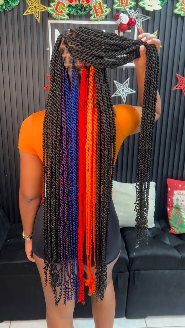 12 Braids Hairstyles: 29 Ideas, From Box Braids to Milkmaid 28 Woman with long black braids featuring blue and orange highlights in a room.