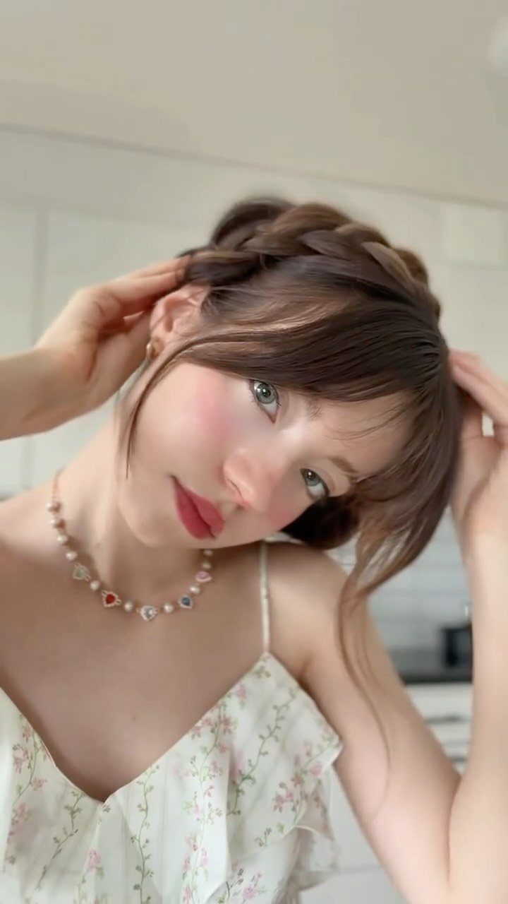 12 Braids Hairstyles: 29 Ideas, From Box Braids to Milkmaid 30 Woman with brown hair styled in a milkmaid braid wearing a floral dress.