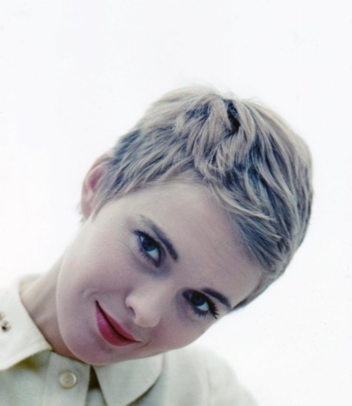 1960s Hairstyles: 7 Ideas from Beehives to Bubble Cuts 5 Woman with a short blonde pixie cut hairstyle wearing a white collared shirt.