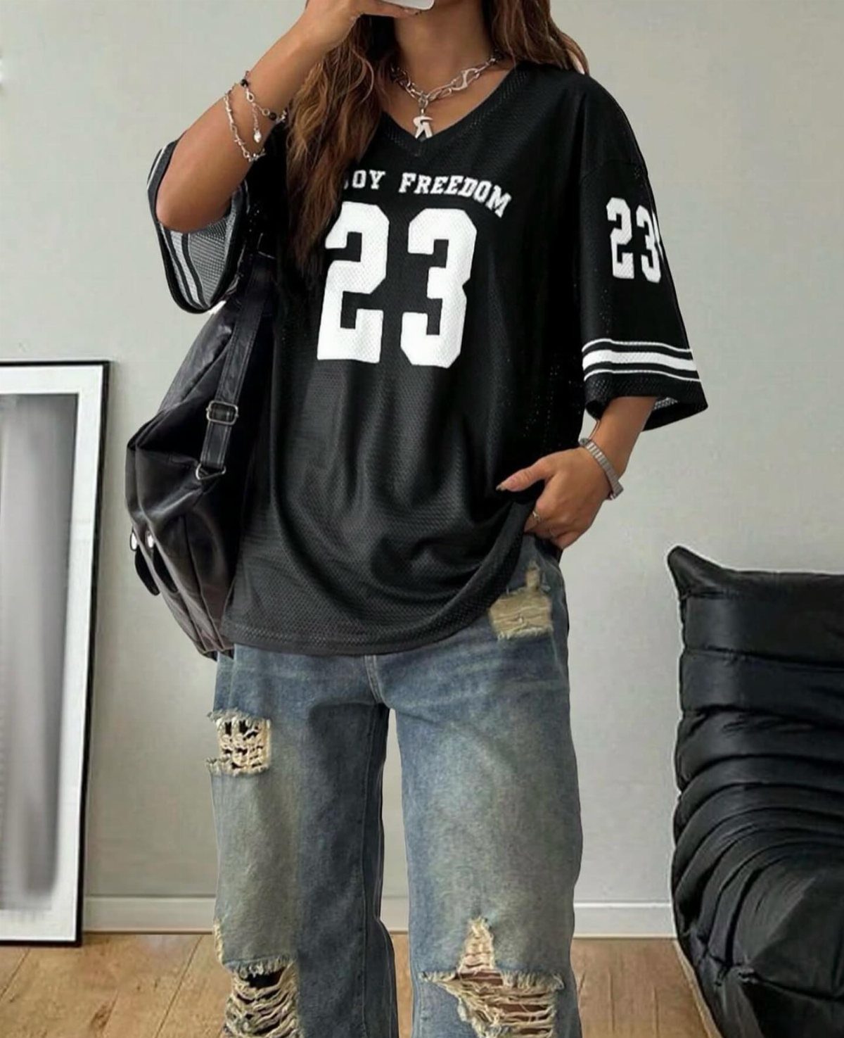 Person wearing a black basketball jersey with number 23 and distressed blue jeans.