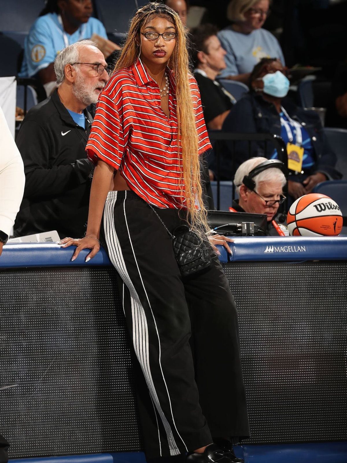 Woman in red striped shirt and black track pants at a basketball game.