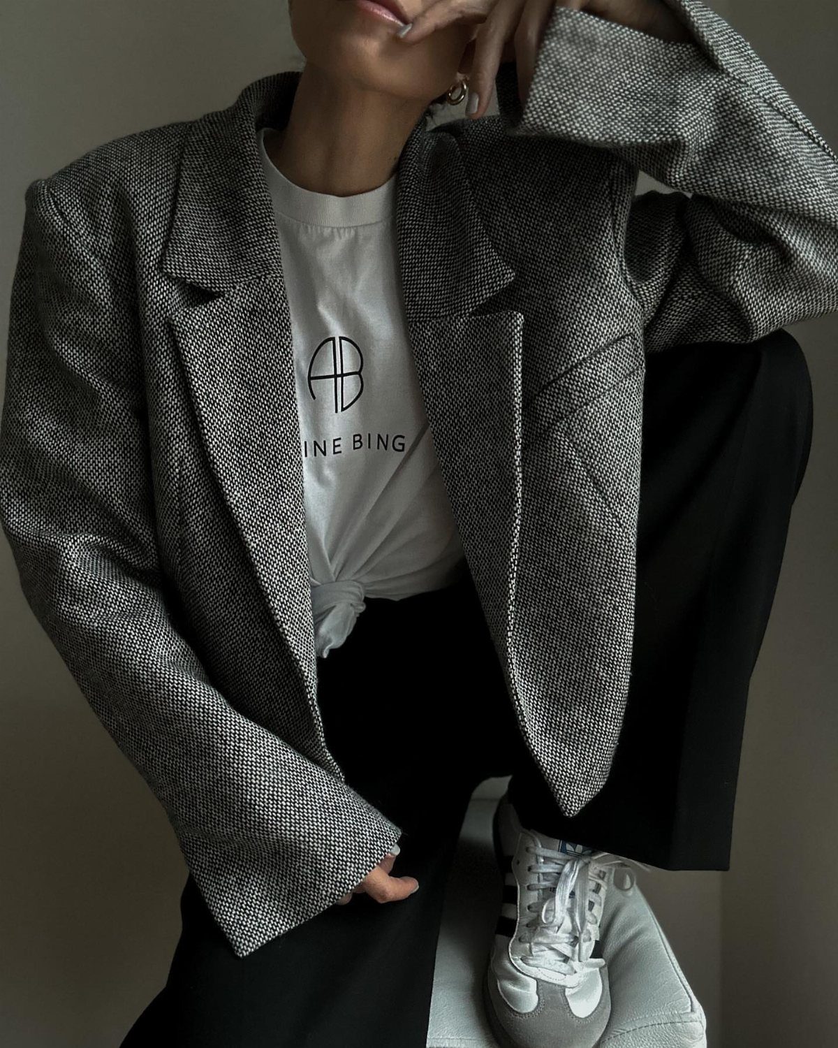 Person wearing a grey textured blazer, white t-shirt, and black baggy trousers.