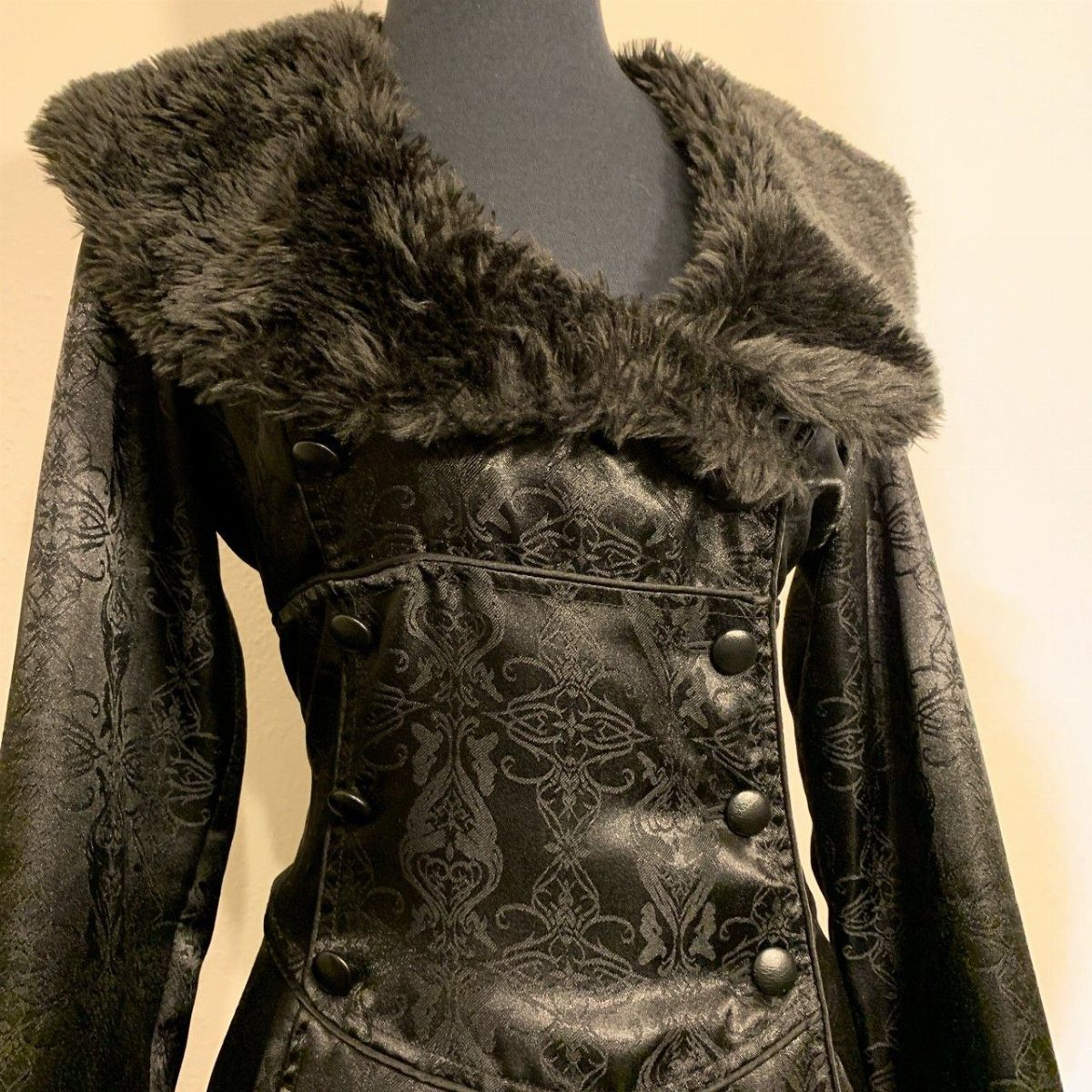 Black patterned leather corset vest featuring a dramatic grey faux-fur collar on a mannequin.
