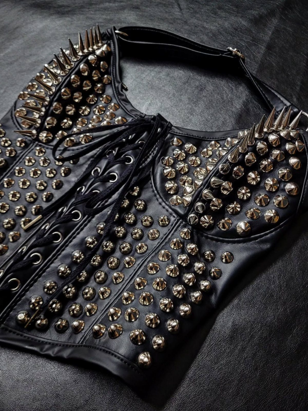 Black leather corset covered in silver metal studs and spikes on black background