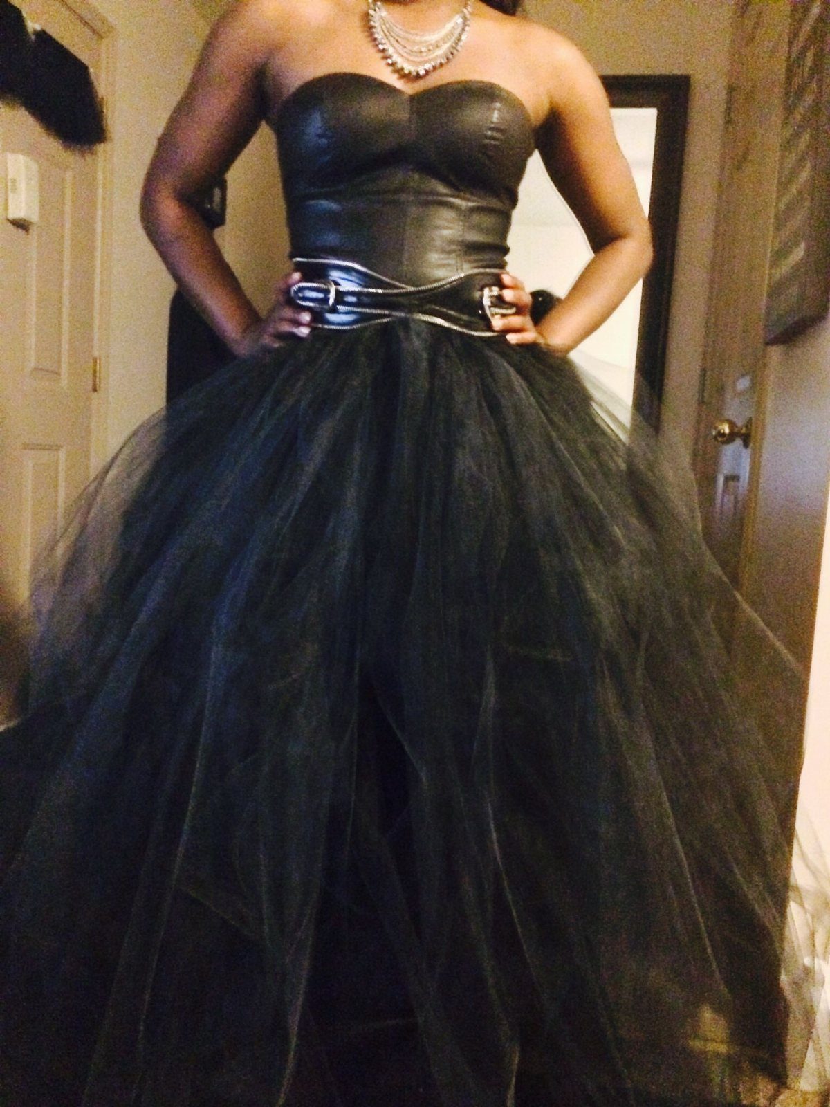 Person wearing a black leather corset paired with a full black tulle skirt.