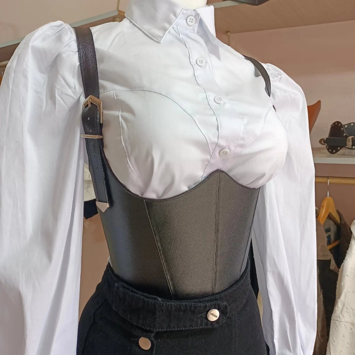 Black leather underbust corset layered over a white long-sleeved button-down shirt.
