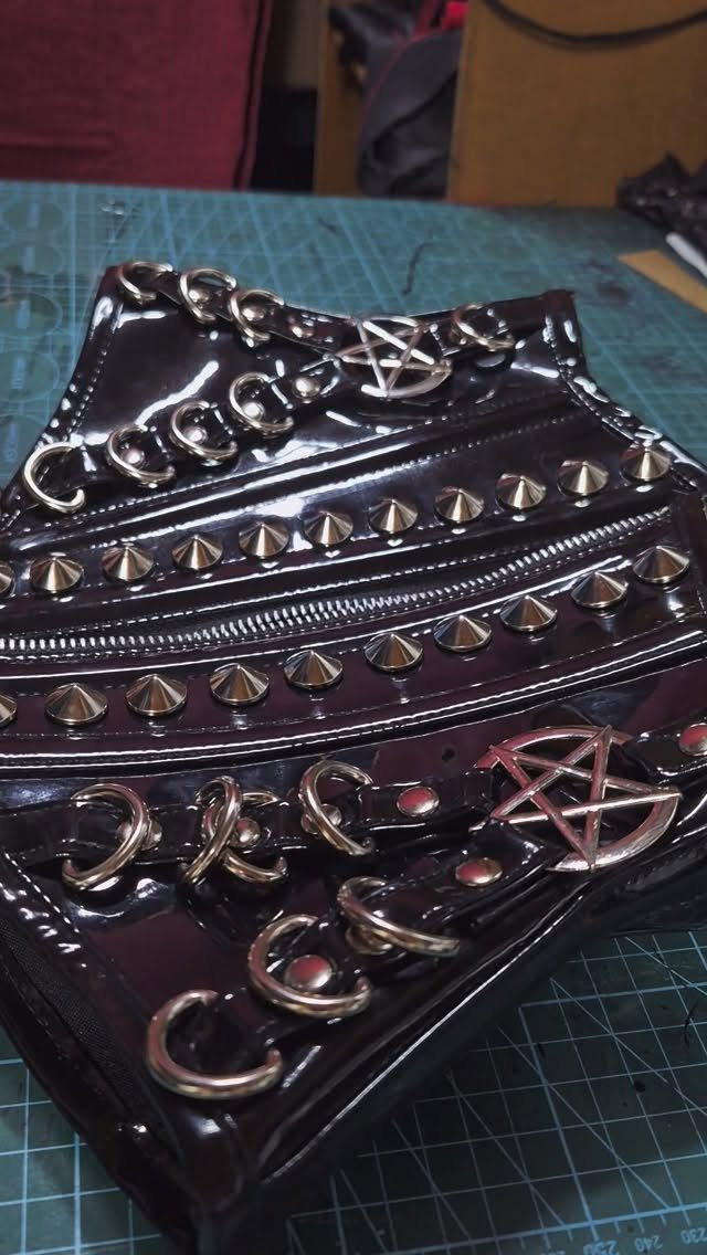 Black leather corset with silver studs and pentagram buckles on a green mat