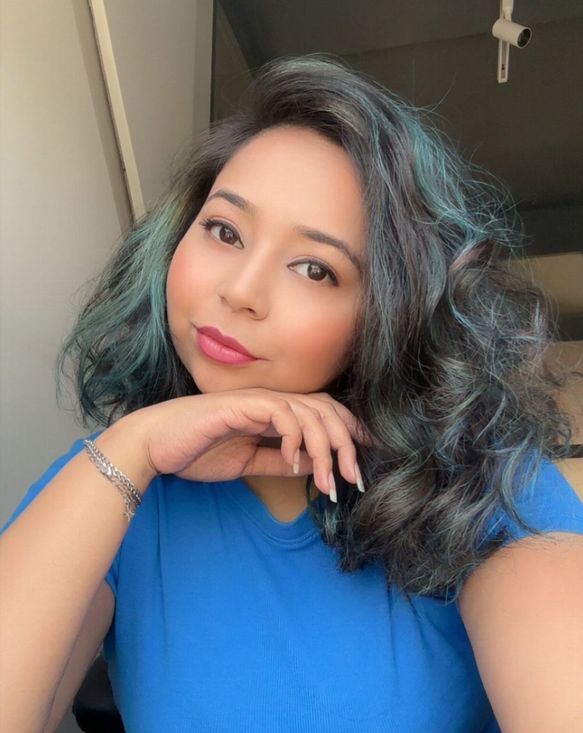 8 Blue Highlights for Brown Hair Ideas and Styles 9 Woman with wavy brown hair and teal blue highlights wearing a blue shirt