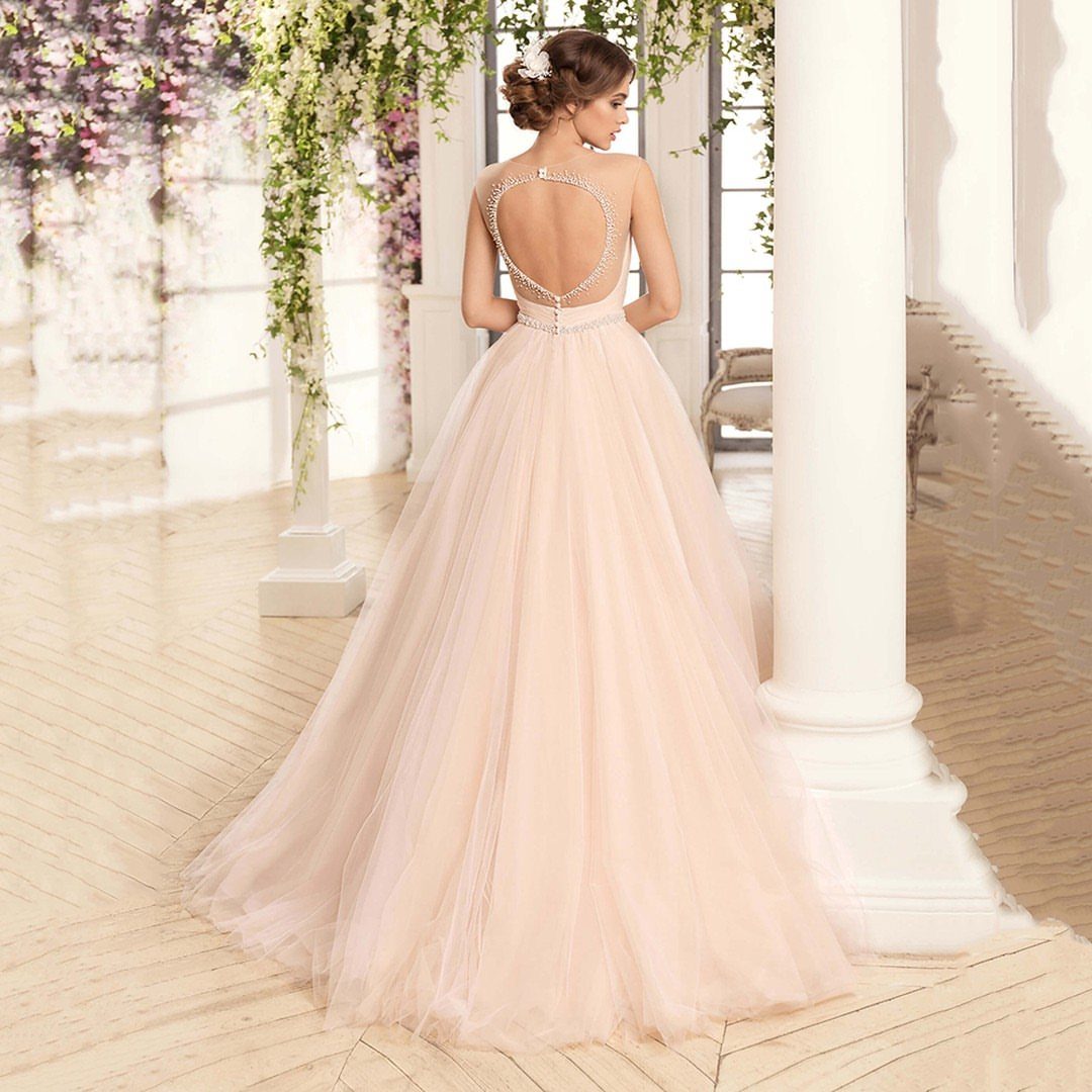 25 Blush Wedding Dress Ideas in Lace, Tulle, Silk and Sequins 23 Woman wearing a blush tulle wedding dress with an open beaded back.