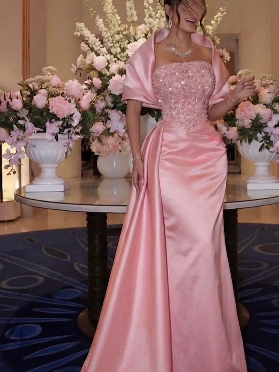 25 Blush Wedding Dress Ideas in Lace, Tulle, Silk and Sequins 8 Woman in a pink gown with a beaded bodice and satin skirt among flowers