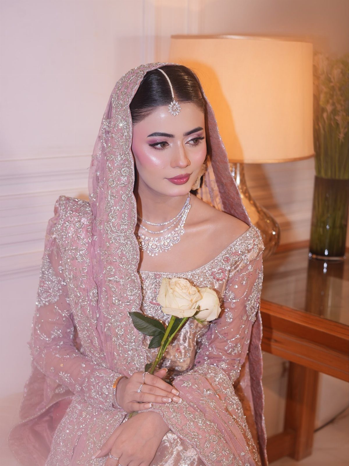 25 Blush Wedding Dress Ideas in Lace, Tulle, Silk and Sequins 7 Woman in a shimmering pink bridal gown and veil holding cream roses