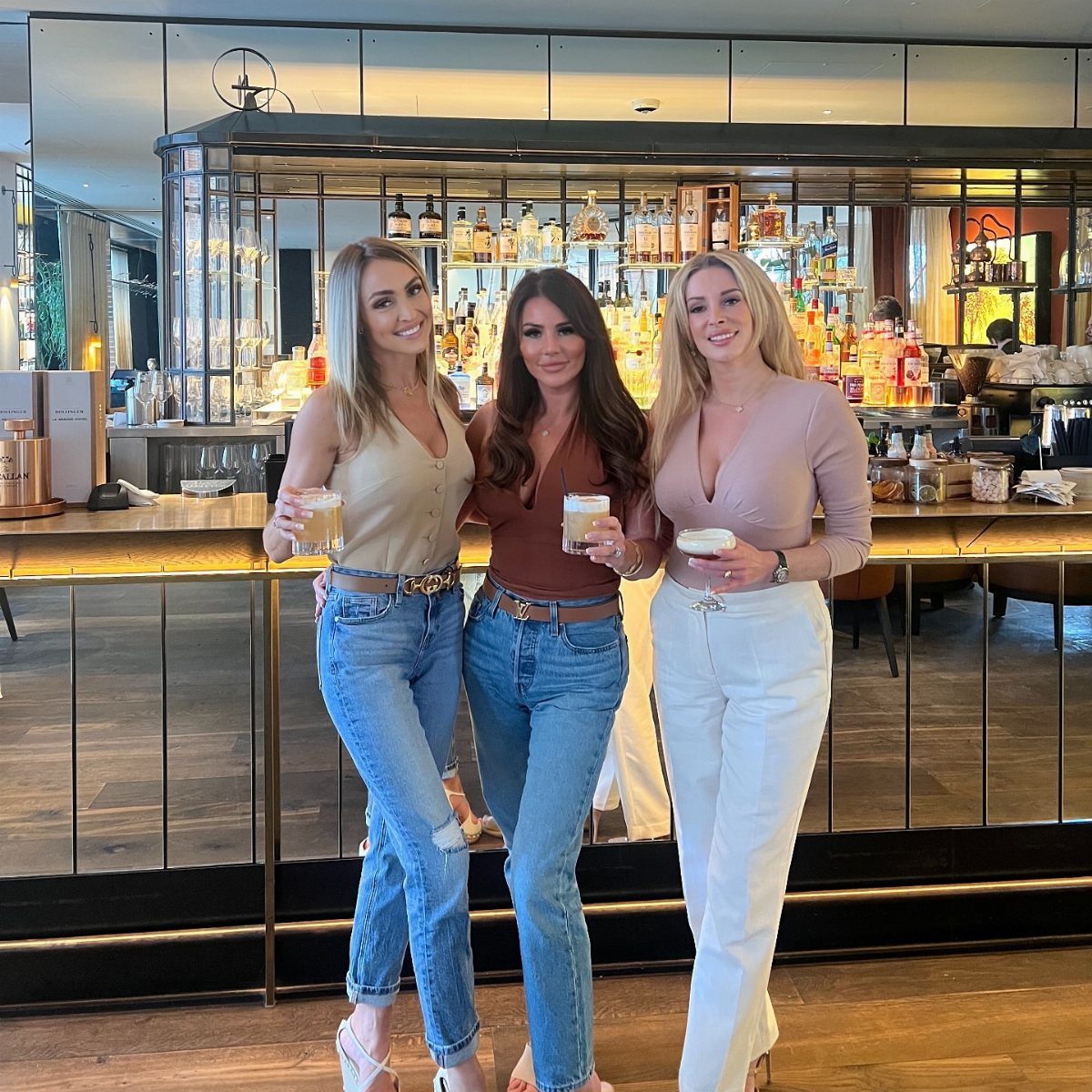 Casual Outfits for Las Vegas: 35 Ideas for Day and Night 32 Three women in dressy tops and jeans posing in a modern bar setting.