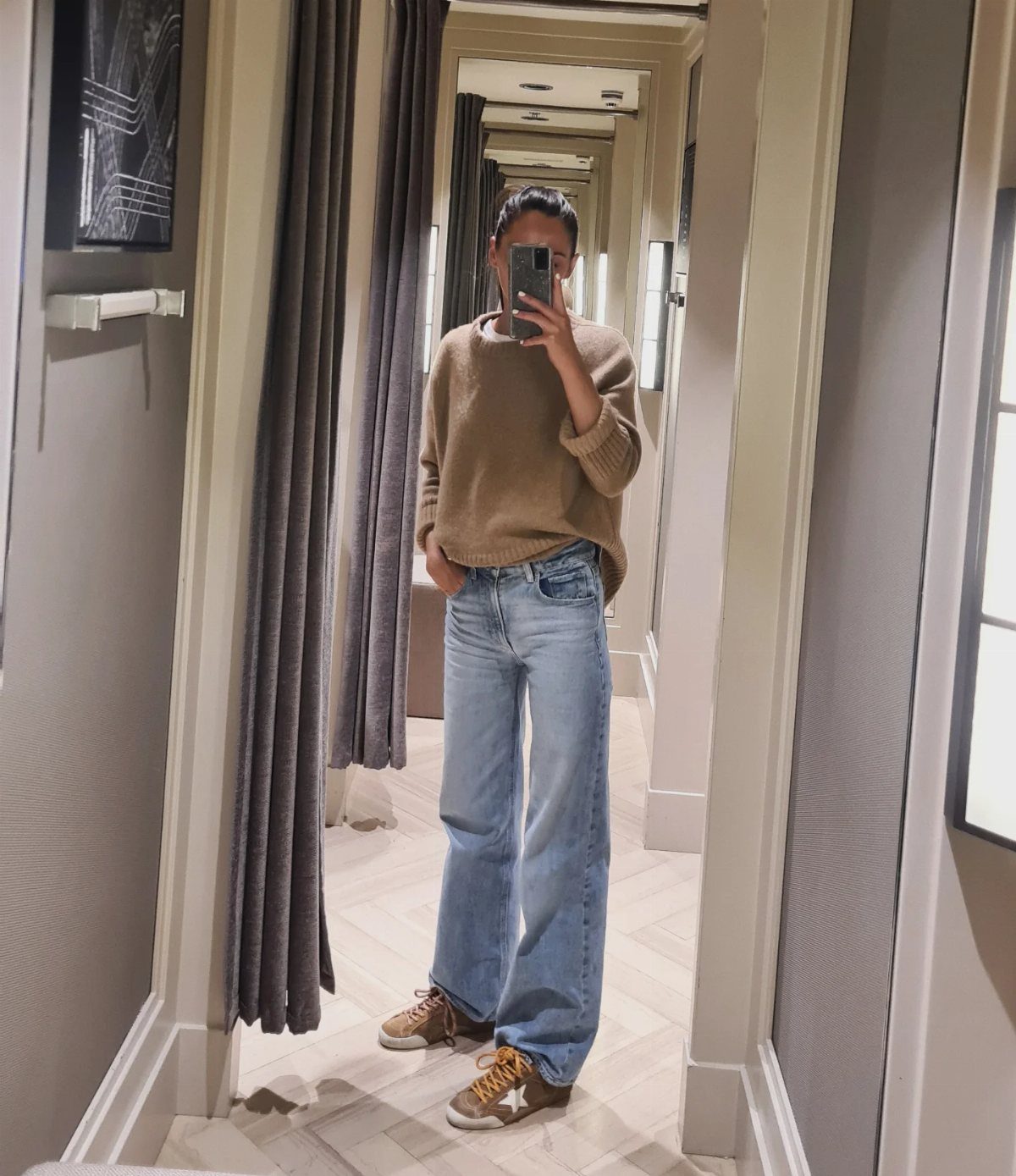 Casual Outfits for Las Vegas: 35 Ideas for Day and Night 7 Person in tan sweater and wide-leg jeans wearing brown star-detailed sneakers.