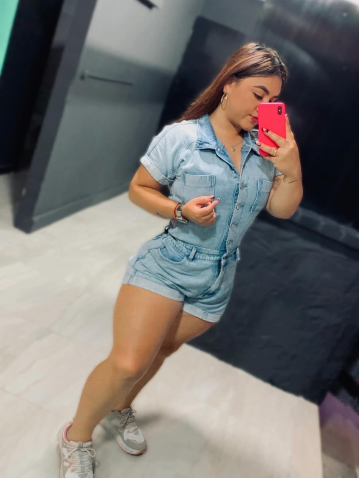 Casual Outfits for Las Vegas: 35 Ideas for Day and Night 12 Woman wearing a light blue denim romper and white sneakers taking a mirror selfie.