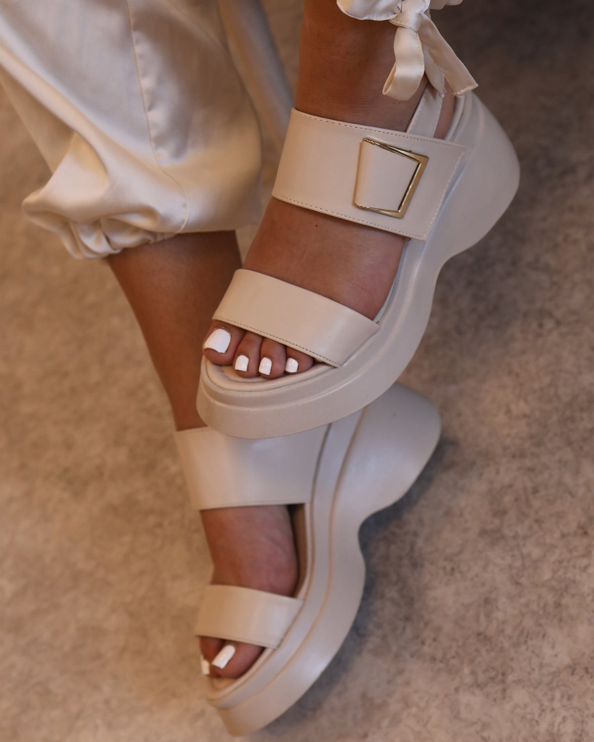 Casual Outfits for Las Vegas: 35 Ideas for Day and Night 8 Off-white platform sandals with gold buckles worn with cream trousers on a carpet.