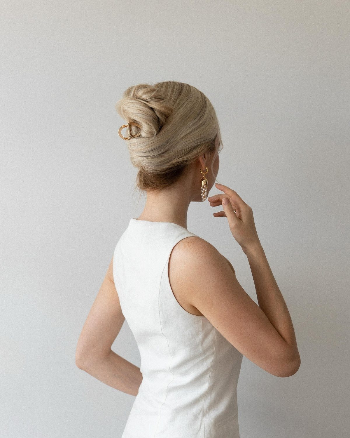 11 Clip Up Hairstyles From French Twists to Half-Up Buns 9 Blonde woman with a high twisted updo secured by a gold clip.
