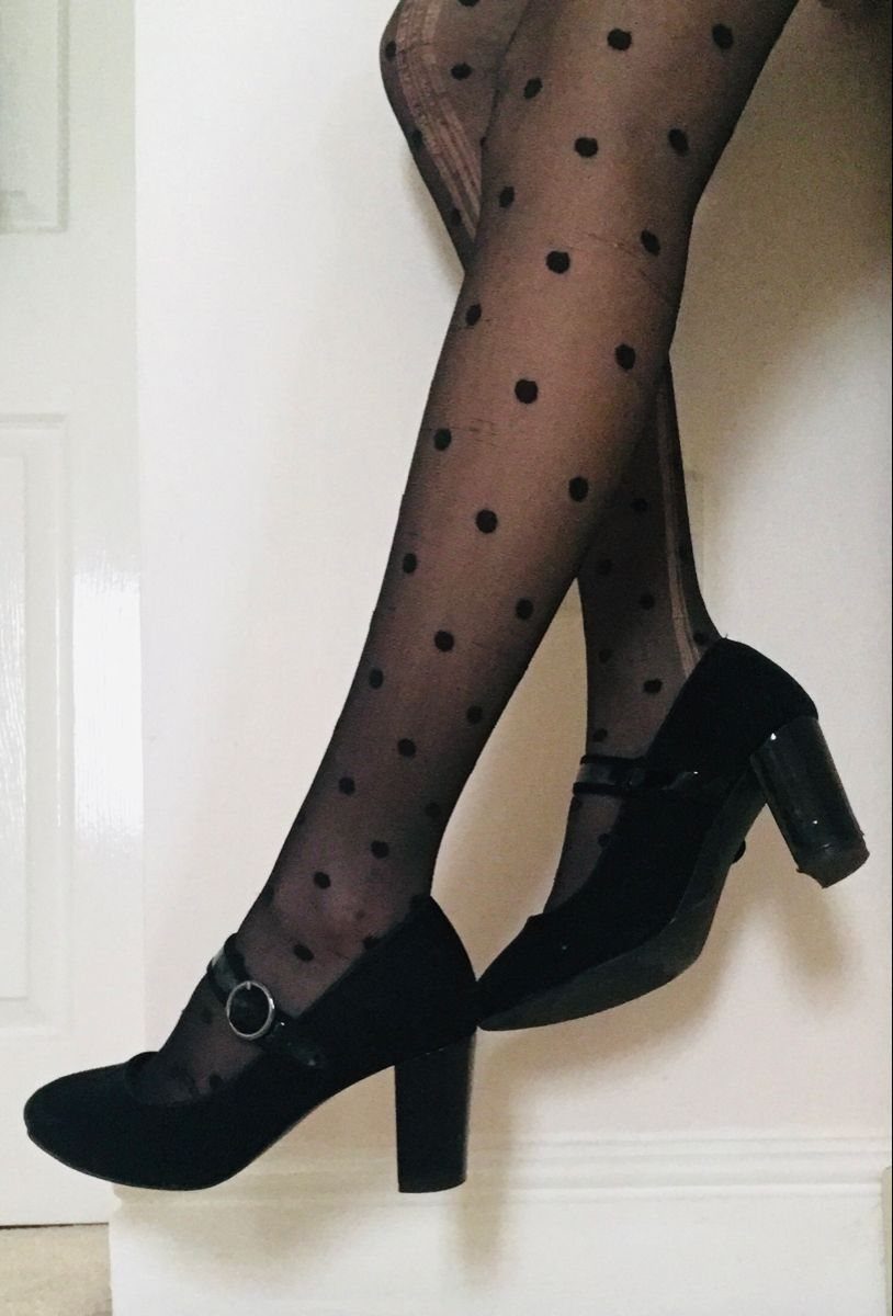 Black block heel pumps worn with sheer black polka dot tights.