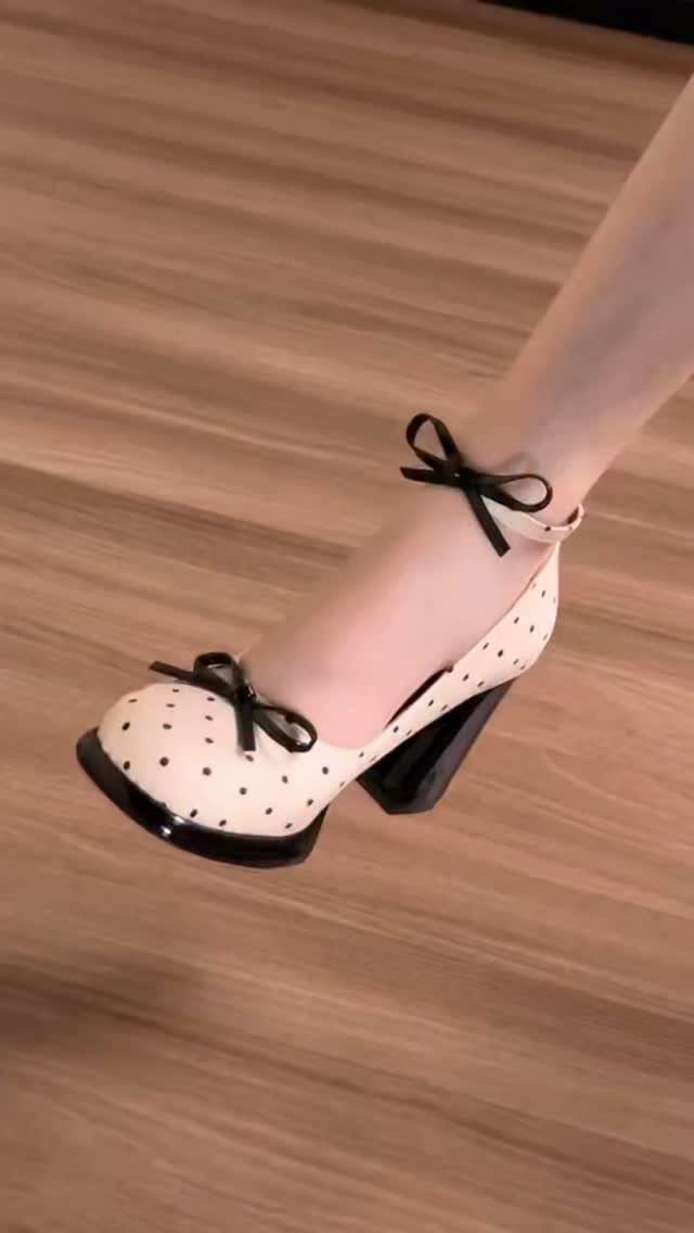 Cream polka dot pumps with black bows and a chunky black block heel.