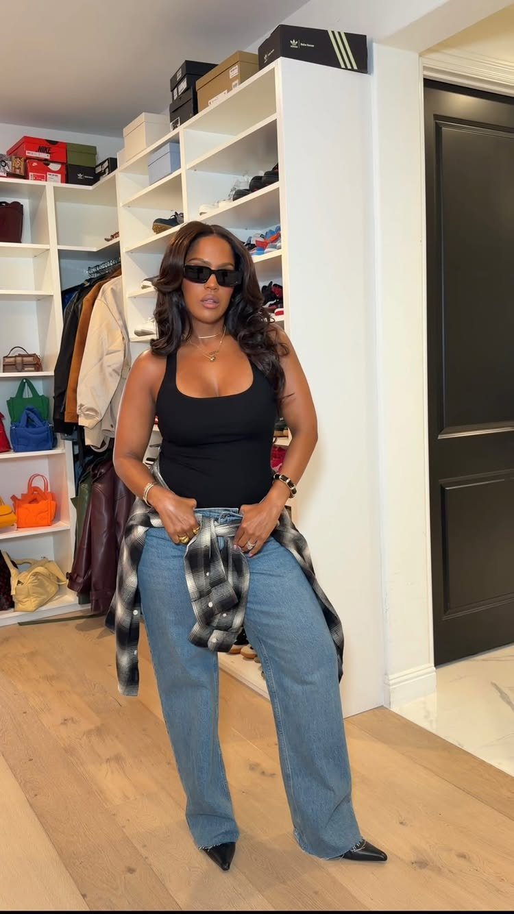 Woman in black tank top, wide-leg blue jeans, and black pointed-toe high heels.