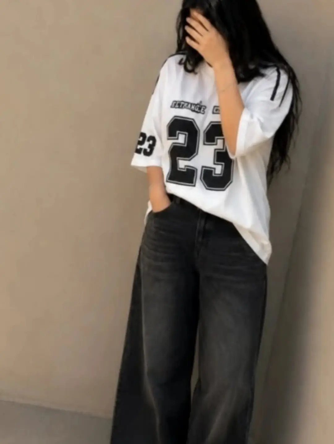Person wearing an oversized white graphic t-shirt and wide-leg black jeans.