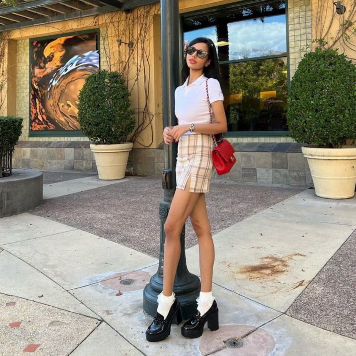 Woman wearing a plaid mini skirt and black platform loafers with white socks.
