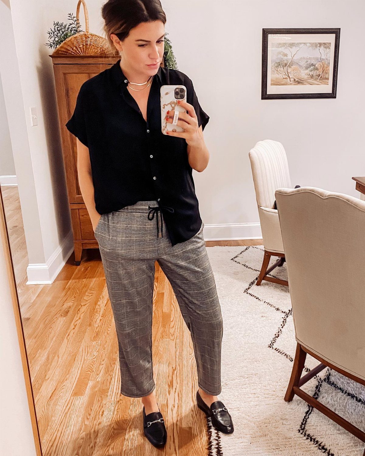 Woman wearing a black button-down shirt, checkered trousers, and black loafers for semi-formal look.
