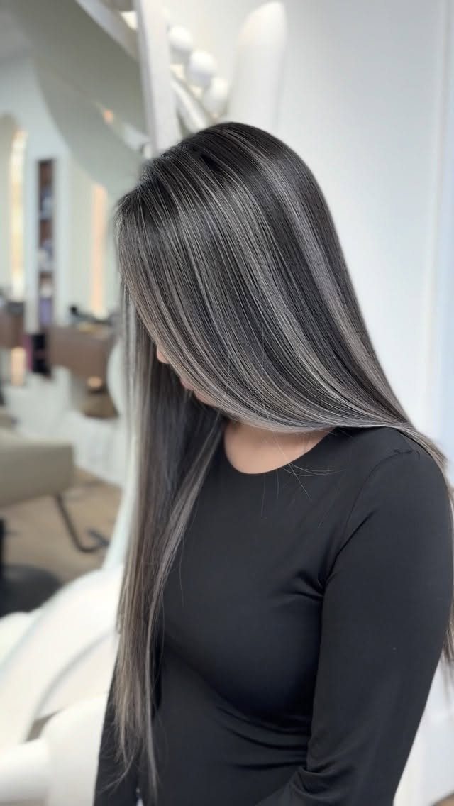 Dark Winter Hair Color: 9 Shades From Black to Burgundy 9 Woman with long straight dark charcoal and silver-grey highlighted hair wearing black shirt