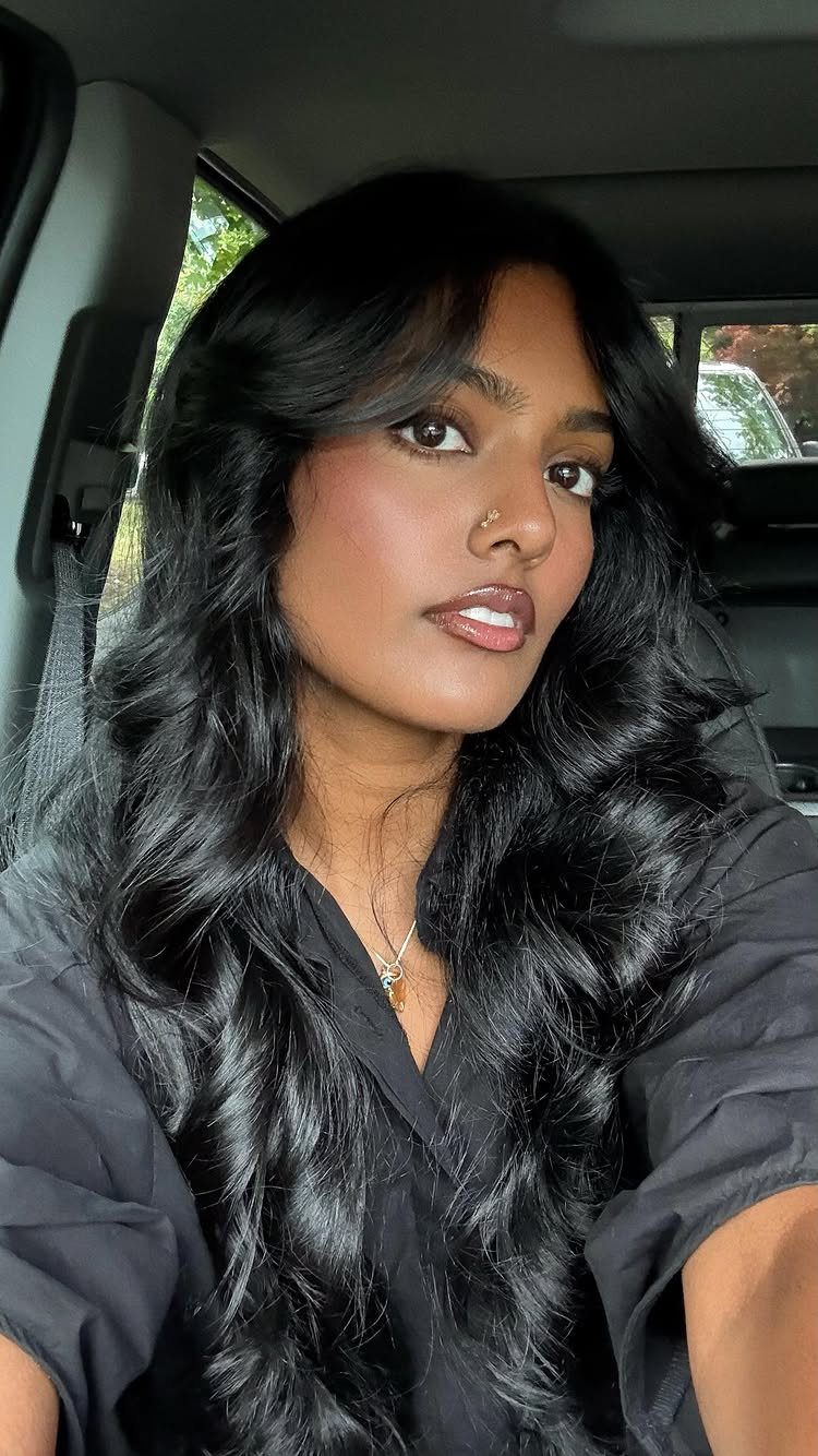 Dark Winter Hair Color: 9 Shades From Black to Burgundy 3 Woman with long, wavy jet black hair wearing a black shirt inside a car.