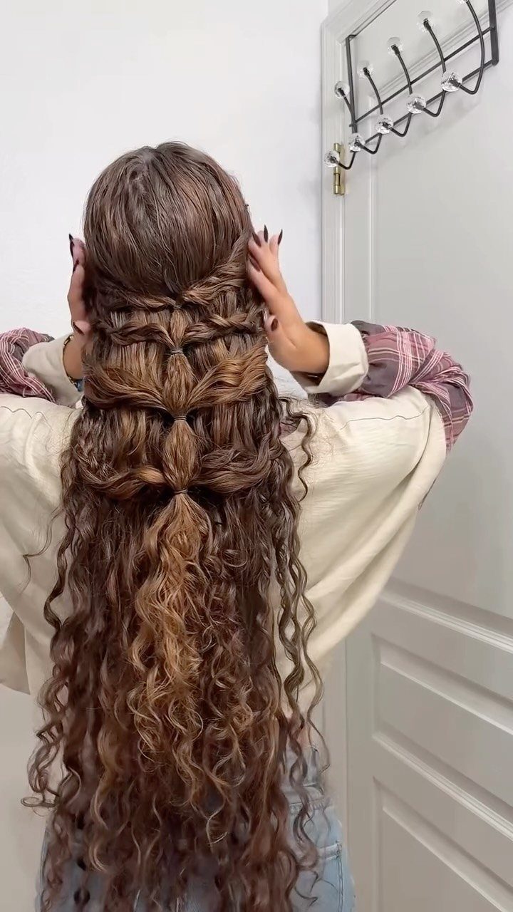 Long curly brown hair styled in a pull-through braid cascading down the back.