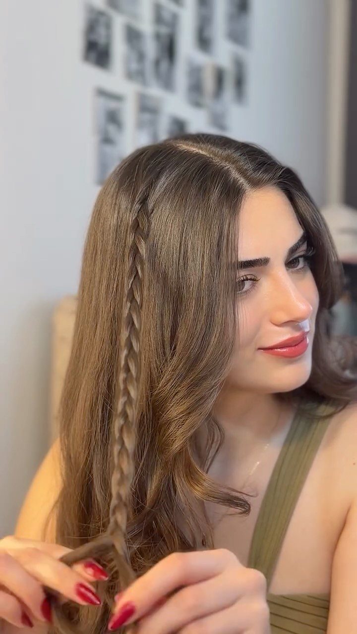 Woman with long brown hair and a side braid wearing a green top.