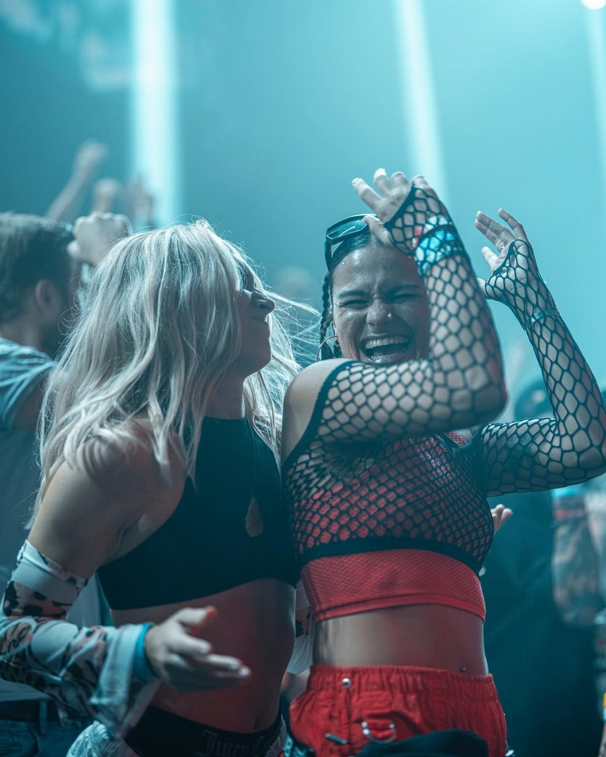 Woman wearing a black mesh top and red crop top dancing at a rave