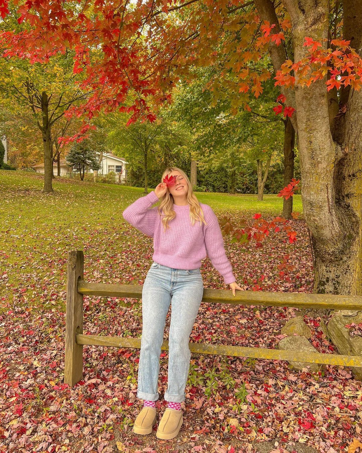 29 Fall Outfits Teens Can Copy, From Grunge to Cowgirl Looks 22 Young woman in purple sweater and blue jeans standing by a wooden fence.