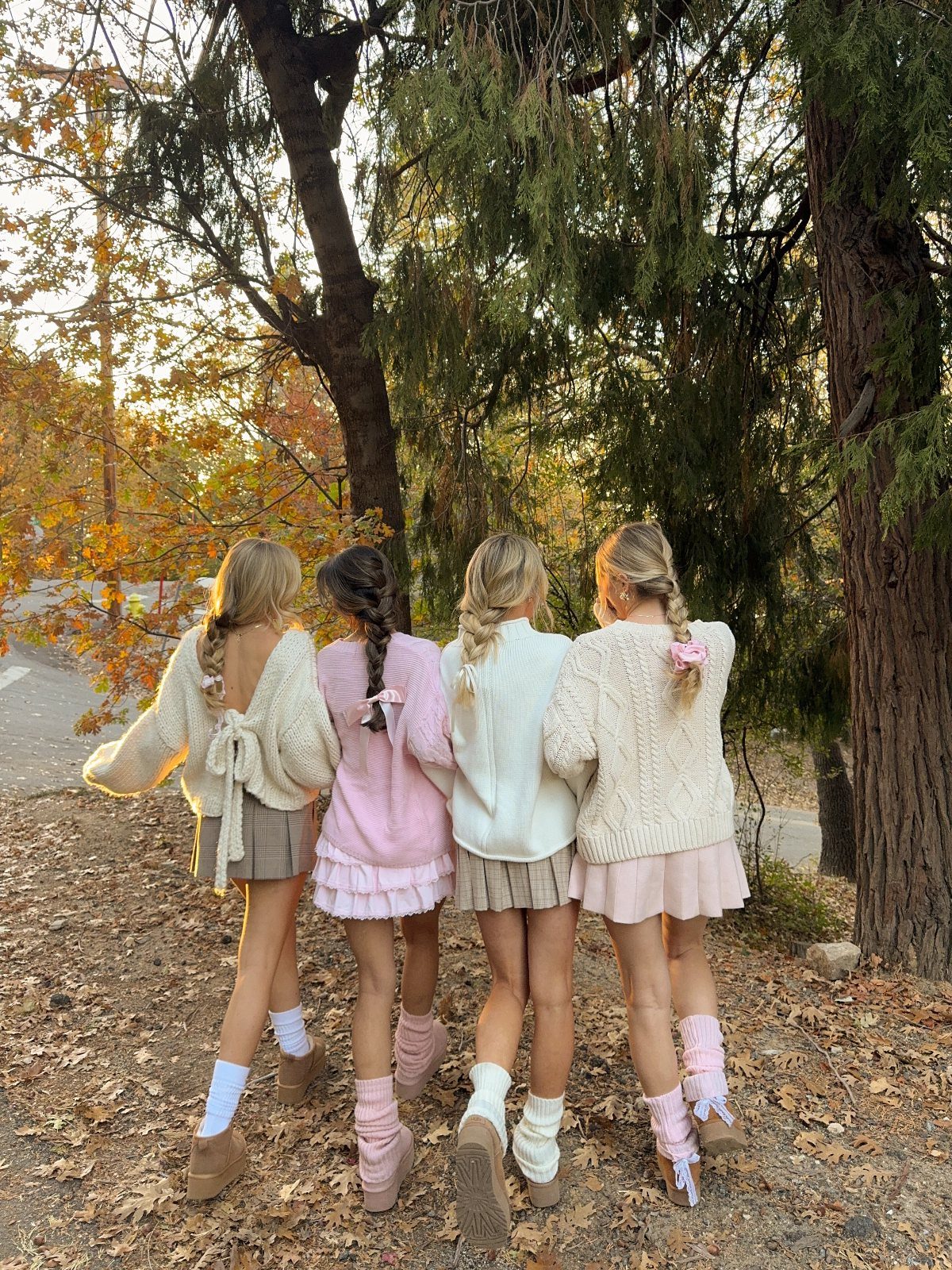 29 Fall Outfits Teens Can Copy, From Grunge to Cowgirl Looks 29 Four teenage girls in cozy autumn sweaters and skirts standing in a wooded area.