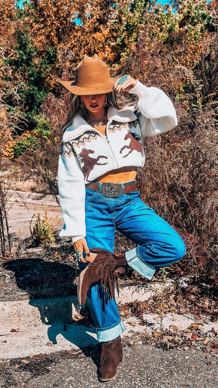 29 Fall Outfits Teens Can Copy, From Grunge to Cowgirl Looks 6 Woman in cowboy hat, cropped sweater, blue jeans, and fringed brown cowboy boots.