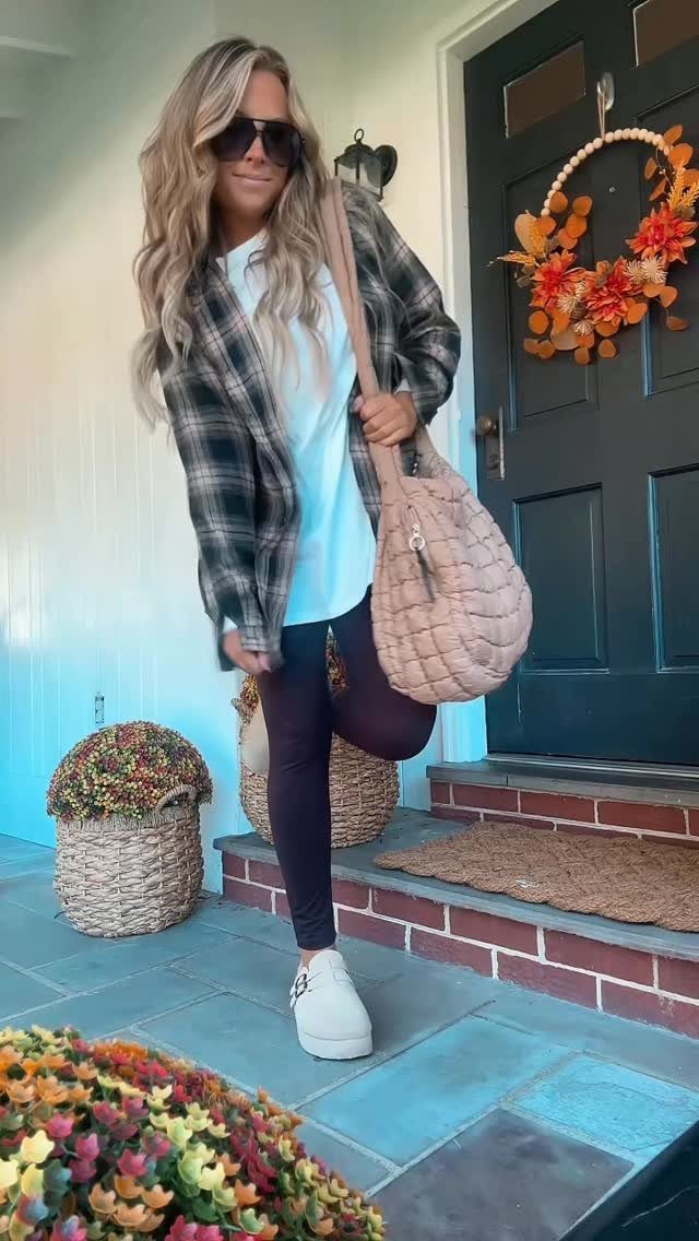 29 Fall Outfits Teens Can Copy, From Grunge to Cowgirl Looks 5 Woman wearing a plaid flannel shirt and dark leggings standing on a porch.