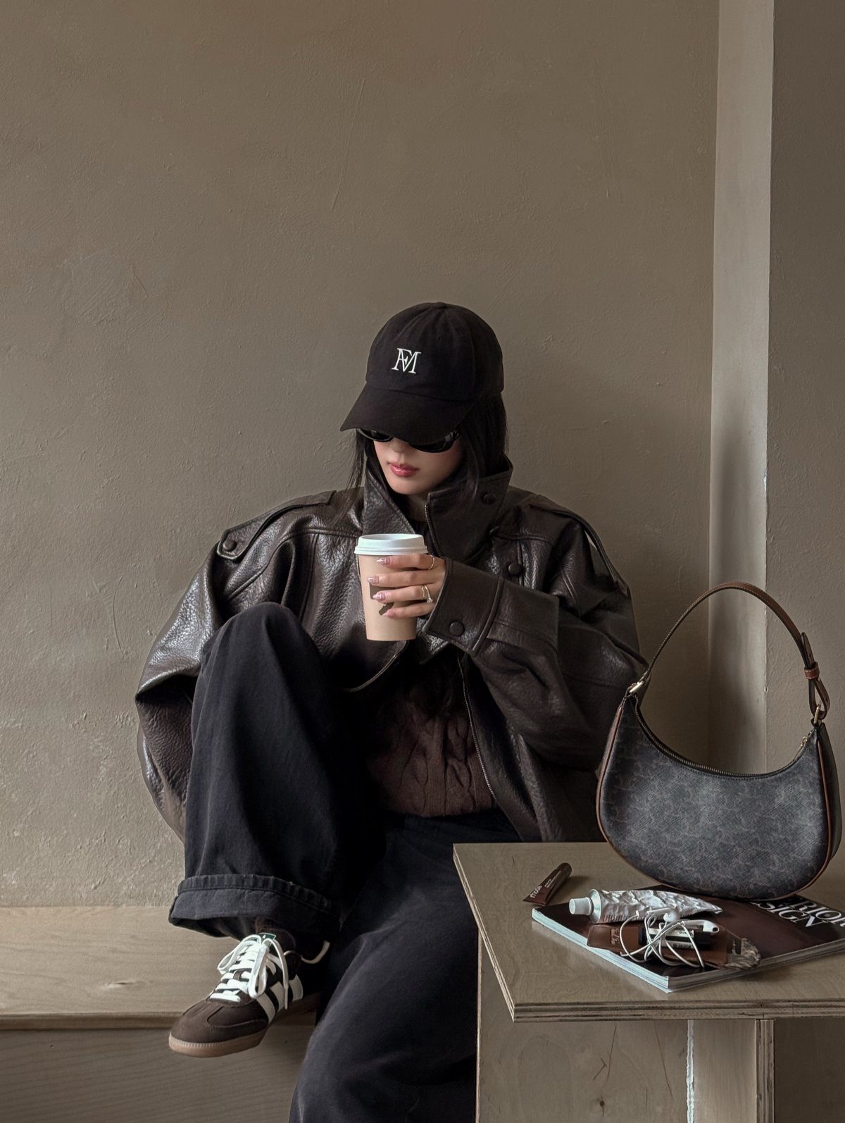 29 Fall Outfits Teens Can Copy, From Grunge to Cowgirl Looks 3 Person in brown leather jacket and black cap holding a coffee cup.