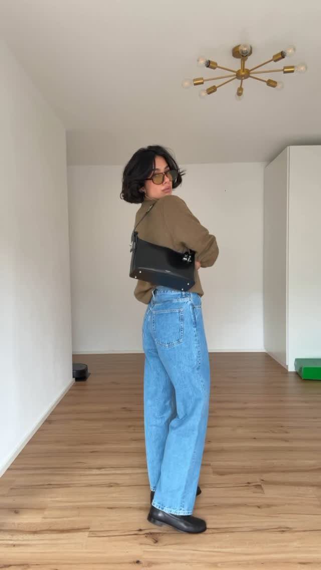 29 Fall Outfits Teens Can Copy, From Grunge to Cowgirl Looks 30 Person wearing olive green sweater and wide-leg blue jeans in a bright room.