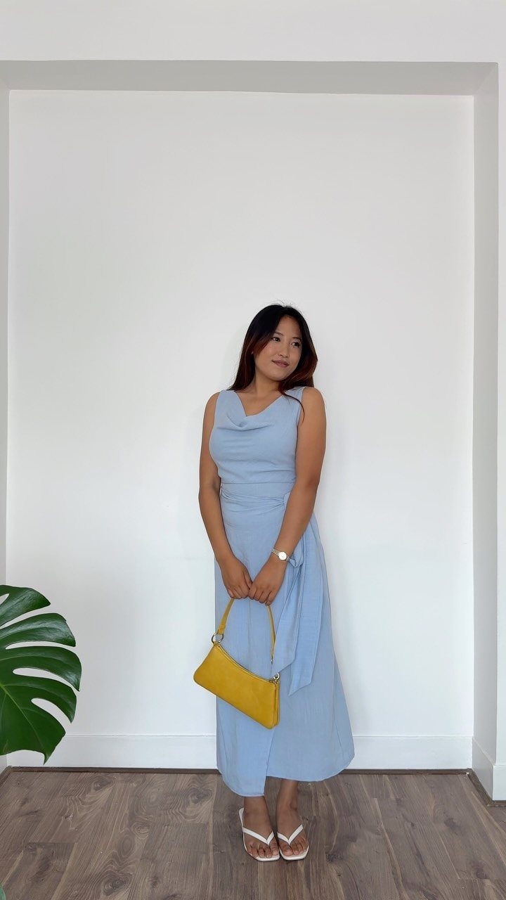 Formal Casual Dresses: 20 Ideas From Shirt Dresses to Velvet 19 Woman in a light blue sleeveless midi dress with a yellow shoulder bag.
