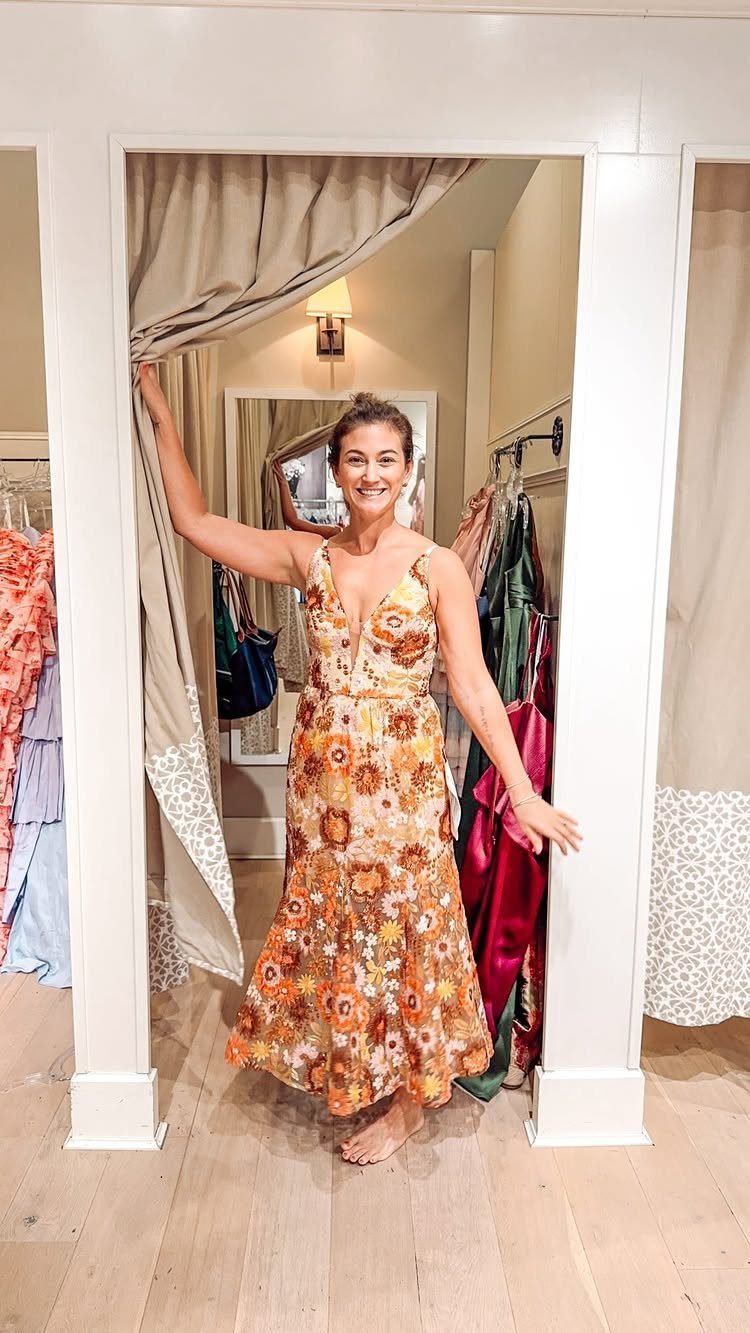 Formal Casual Dresses: 20 Ideas From Shirt Dresses to Velvet 8 Woman in a floral orange midi dress posing in a clothing store dressing room