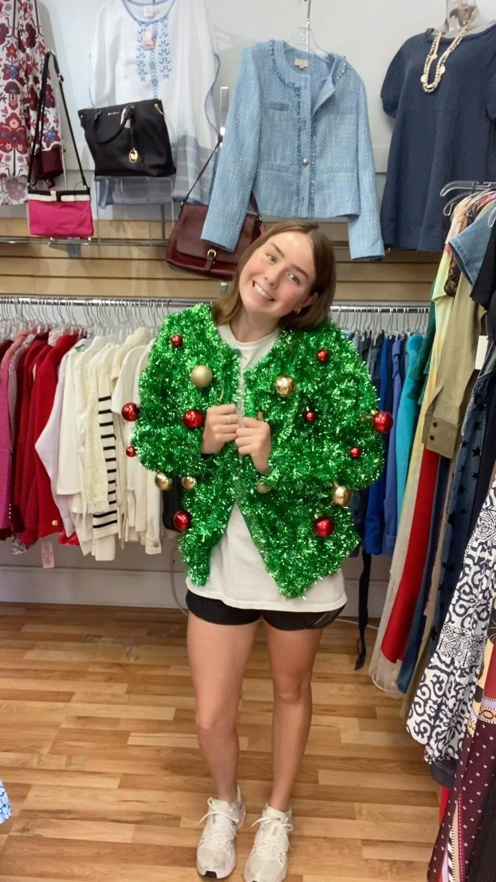 Woman wearing a green tinsel garland with ornaments as an ugly Christmas sweater.