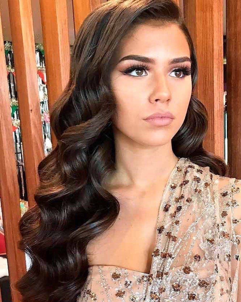 16 Good Hairstyles for Curly Hair, From Pixie to Long Layers 14 Woman with long dark brown hair styled in voluminous side-swept curls and beads.