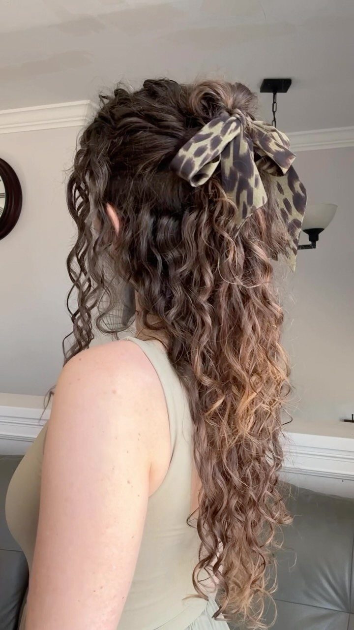 16 Good Hairstyles for Curly Hair, From Pixie to Long Layers 3 Long brown curly hair tied in a ponytail with a leopard print bow.