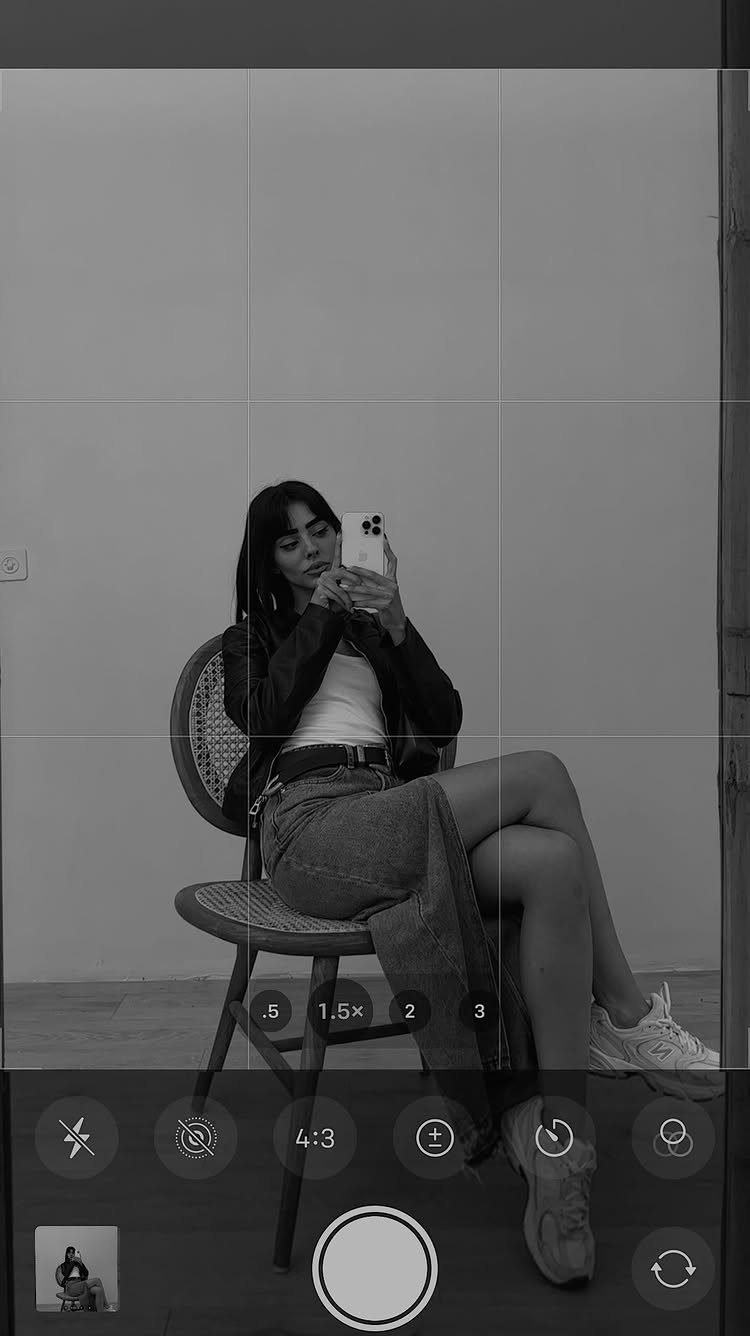 18 Gray Skirt Outfit Ideas From Mini to Maxi and Satin 11 Woman sitting in a chair wearing a long gray denim skirt and sneakers.
