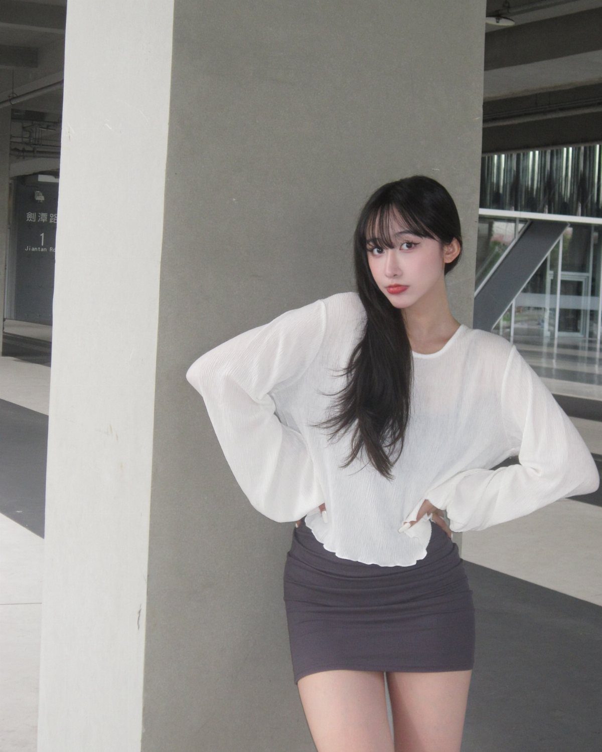 18 Gray Skirt Outfit Ideas From Mini to Maxi and Satin 4 Woman wearing a white blouse and a short gray mini skirt posing outdoors.