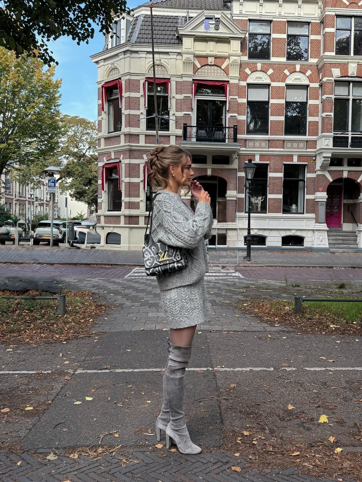 18 Gray Skirt Outfit Ideas From Mini to Maxi and Satin 8 Woman wearing a gray chunky sweater, gray mini skirt, and tall gray boots.