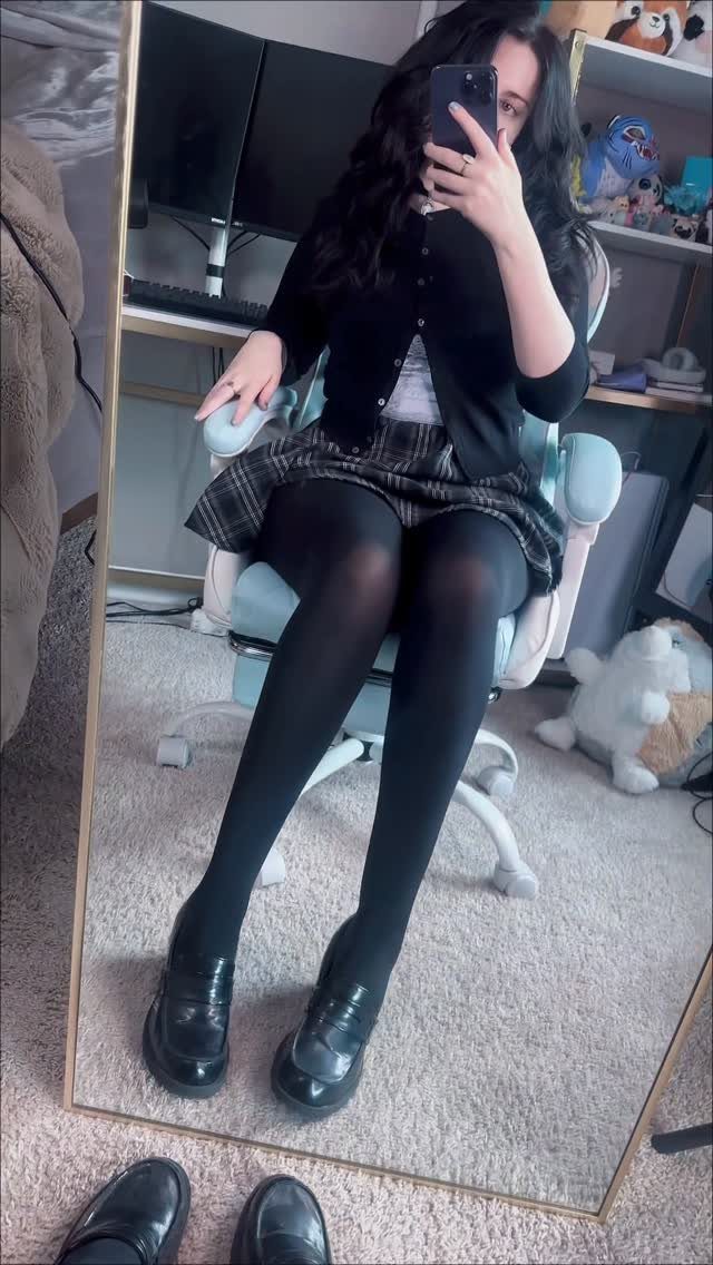 18 Gray Skirt Outfit Ideas From Mini to Maxi and Satin 7 Person in gray plaid mini skirt, black tights, and black loafers posing in mirror.