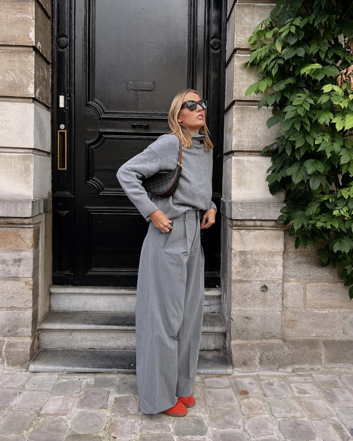 10 Grey Dress Pants Outfit Ideas for Work and Weekends 3 Woman in grey knit sweater and wide-leg grey pants wearing red shoes.