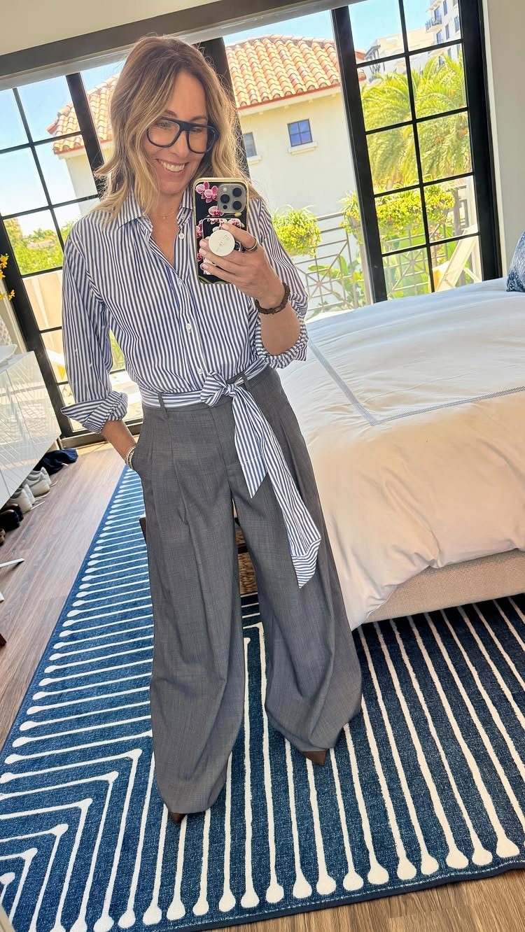 10 Grey Dress Pants Outfit Ideas for Work and Weekends 8 Woman in striped shirt and wide-leg grey dress pants taking a mirror selfie.