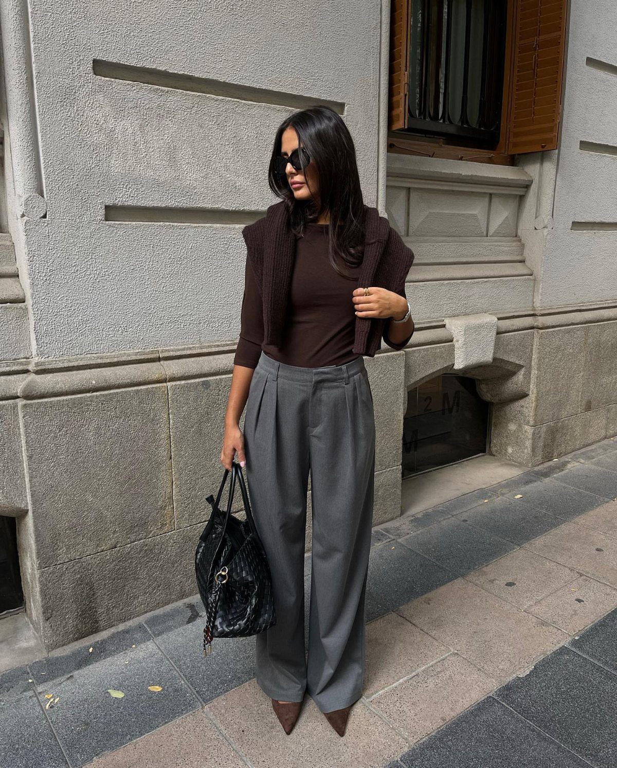10 Grey Dress Pants Outfit Ideas for Work and Weekends 10 Woman in dark brown top and wide-leg grey dress pants with brown pointed heels.