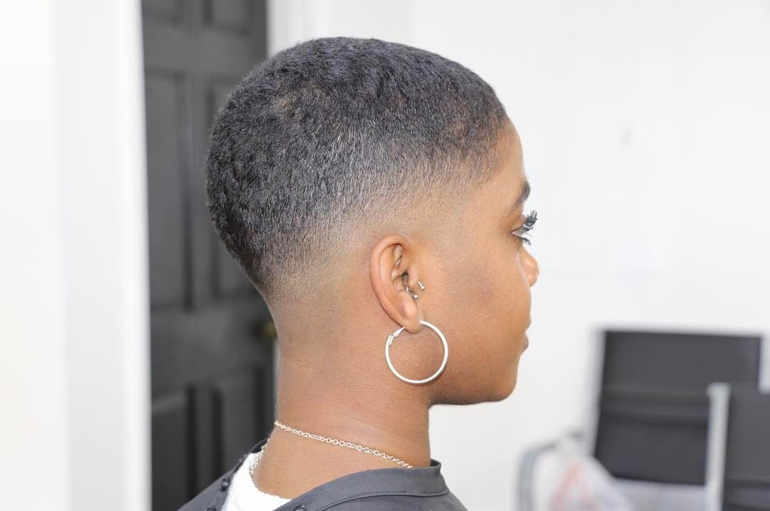Person with a curly buzz cut and faded sides wearing a silver hoop earring.